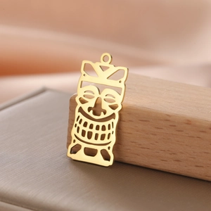 Detailed view of hollow 18K gold plated Tiki mask pendant on a wooden prop