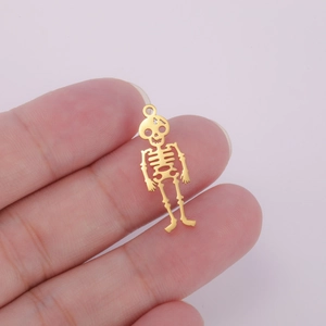 Macro shot of gold hollow skeleton pendant held by hand showing precise size and detail