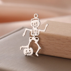 Macro detail of dancing skeleton and pumpkin pendant in polished stainless steel