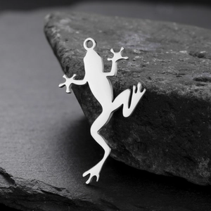 Polished stainless steel frog pendant charm for DIY jewelry making on stone background
