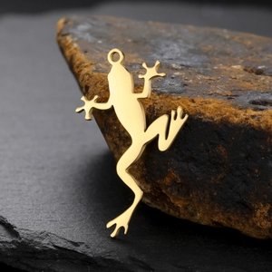 Macro view of golden frog metal charm on natural stone, DIY jewelry accessory detail