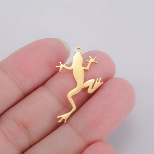 Macro view of gold frog pendant in hand showing tiny dimensions and polished metal finish