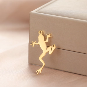 Close-up of golden frog pendant in stainless steel on a champagne jewelry box edge