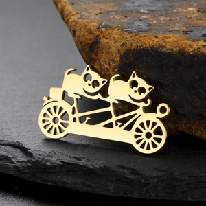 Vue détaillée du pendentif doré découpé représentant des chatons à vélo pour bijoux
