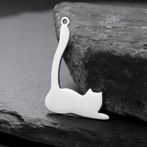 Polished stainless steel cat pendant on dark rock background, cute minimalist jewelry charm