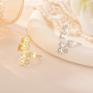 Detail of gold and silver open rings with hollow vine patterns on minimal background