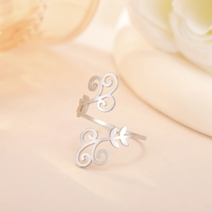 Macro view of silver-tone cutout vine ring with elegant floral patterns on beige background