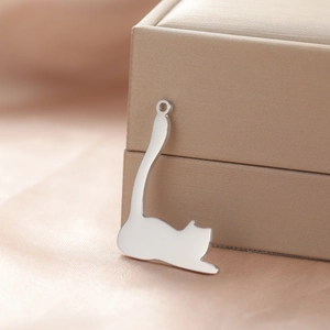 Macro shot of polished stainless steel kitten pendant on soft champagne fabric