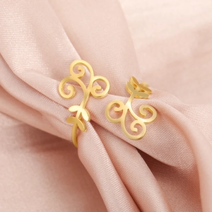 Macro shot of gold stainless steel open ring with intricate vine filigree on satin background