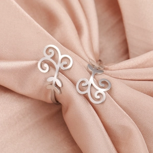 Macro shot of polished silver heart vine earrings on soft pink silk background