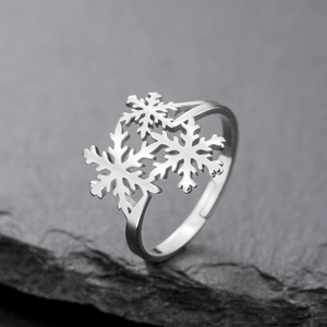 Macro detail of silver snowflake rings with delicate cut-outs on a dark stone surface
