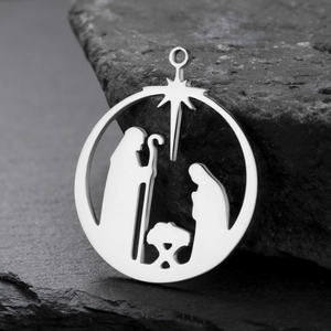 Detailed view of polished stainless steel Nativity scene pendant on a dark stone background
