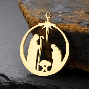 Macro shot of gold stainless steel Nativity scene hollow round pendant on a stone base
