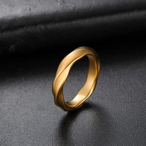 Macro shot of minimalist gold stainless steel twisted ring with polished wavy texture