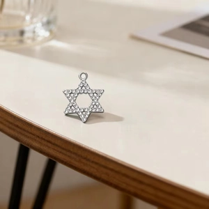 Sparkling David Star pendant in stainless steel with crystal accents on a wooden desk