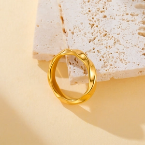 Polished gold mobius twisted stainless steel ring displayed on natural stone