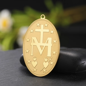 Detailed macro view of gold Virgin Mary pendant back showing M cross and stars symbol