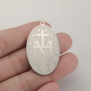 Macro detail of silver stainless steel Virgin Mary oval pendant with religious icons
