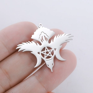 Macro detail of silver raven pendant with pentagram and crescent moon held by fingers