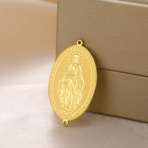 Macro detail of gold Virgin Mary oval charm with religious engraving and dual holes