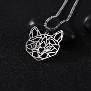 Macro-opname van zilveren geometrische kattenhanger met kralenketting op donkere stenen