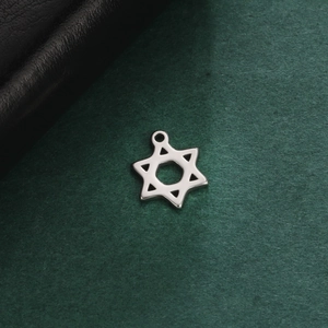 Polished silver stainless steel hexagram pendant for DIY necklaces on a dark green surface