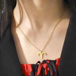 Gros plan d'un collier avec pendentif Bélier en or 18 carats porté par un mannequin en costume