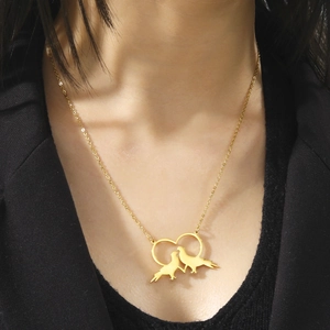 Collana dorata con pendente a cuore e due uccelli indossata su abito professionale nero