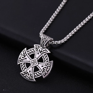 Detailed close-up of a vintage silver alloy Celtic cross necklace on a black leather background