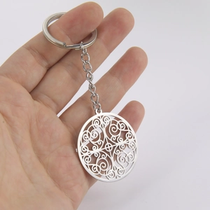 Polished stainless steel keychain with intricate circular hollow pattern charm on white background