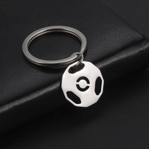 Polished stainless steel hollow soccer keychain on black leather background