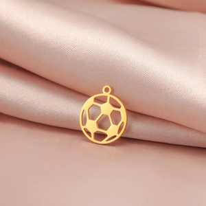 Vue macro du pendentif de football creux en or 18K sur fond de soie rose luxueux