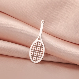 Detailed close-up of a silver tennis racket pendant on soft pink silk fabric