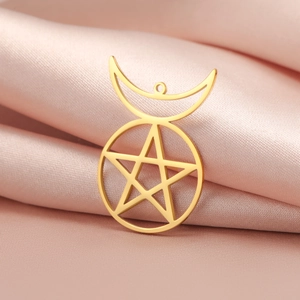 Macro shot of 18K gold plated pentagram and moon pendant on soft pink silk