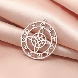 Detailed macro view of silver steel Wiccan moon pendant on soft pink satin fabric background