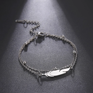 Detalle de pulsera de doble capa en acero inoxidable con colgante de pluma y cuentas