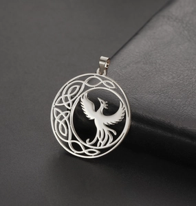 Macro detail of silver phoenix pendant with celtic knot on black leather surface