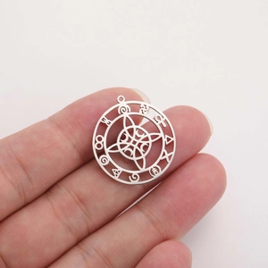 Macro shot of silver stainless steel celestial pendant with intricate occult engravings