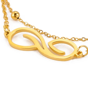 Detalle de una tobillera de doble capa chapada en oro de 18K con dije de onda de infinito
