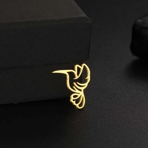 Detailed view of a gold hollow hummingbird pendant on a textured black jewelry gift box