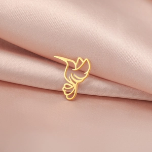 Detail of a minimalist golden hummingbird charm pendant on elegant pink silk background