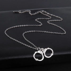 Detailed close-up of a silver-tone handcuff pendant necklace on black leather texture