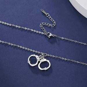 Close-up of a silver handcuff pendant necklace with adjustable chain on blue background