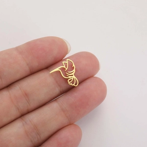 Close-up of gold hollow hummingbird charm being held to show small scale and detail