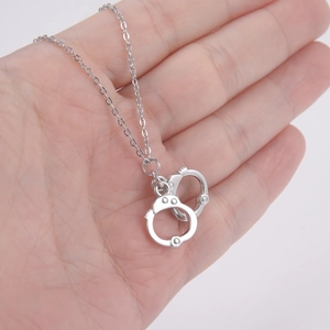 Hip hop style silver handcuff pendant necklace displayed on a hand for size scale