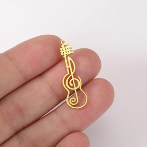 Detailed macro of a hollow gold guitar and musical note pendant in stainless steel