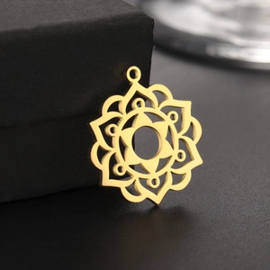 Macro shot of gold stainless steel mandala flower pendant on black jewelry box