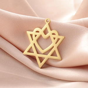Makroaufnahme von goldenem Hexagramm-Herz-Anhänger auf glattem rosa Seidenstoff