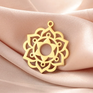 Macro detail of a gold hollow mandala pendant with a polished finish on pink silk fabric