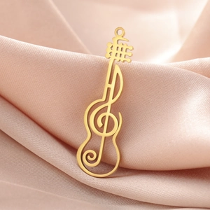 Macro view of a gold musical G-clef guitar pendant on a soft pink satin fabric